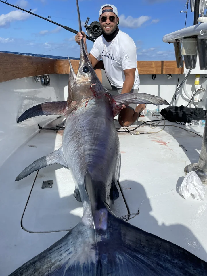 An angler on deck with a giant swordfish caught off Miami