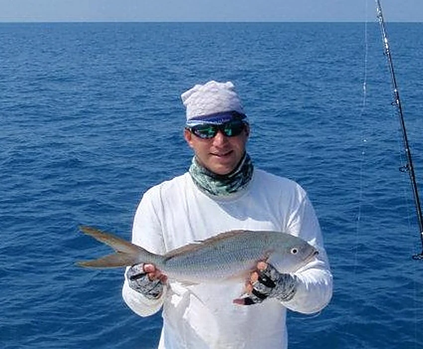 An angler holding a large yellowtail snapper boatside off Miami